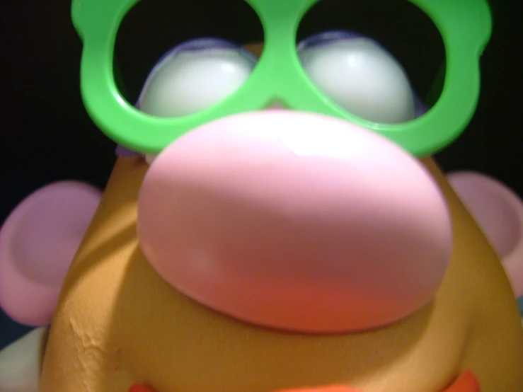 the toy character has green sunglasses and is sticking out his tongue