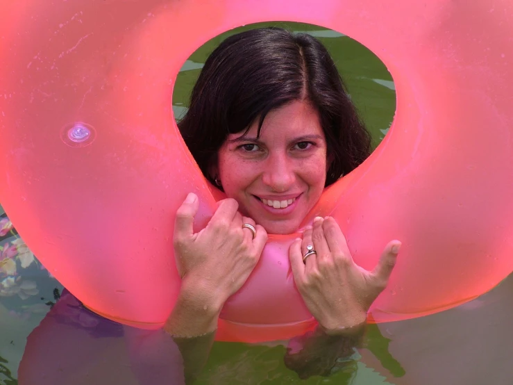 a woman floating on a pink raft holding on to the side of her neck