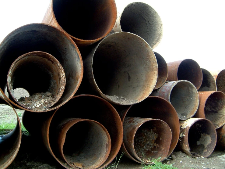 a pile of rusty old pipe laying in the grass