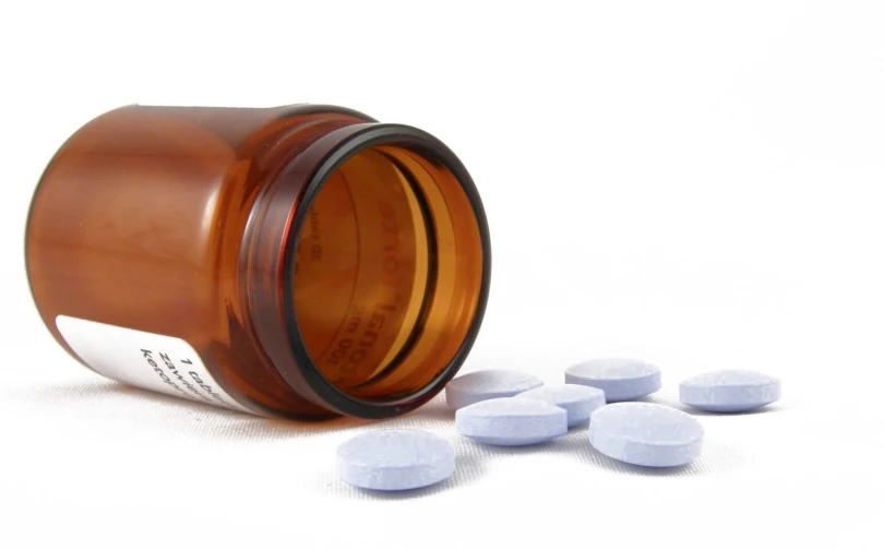 pills sitting next to an open medicine bottle
