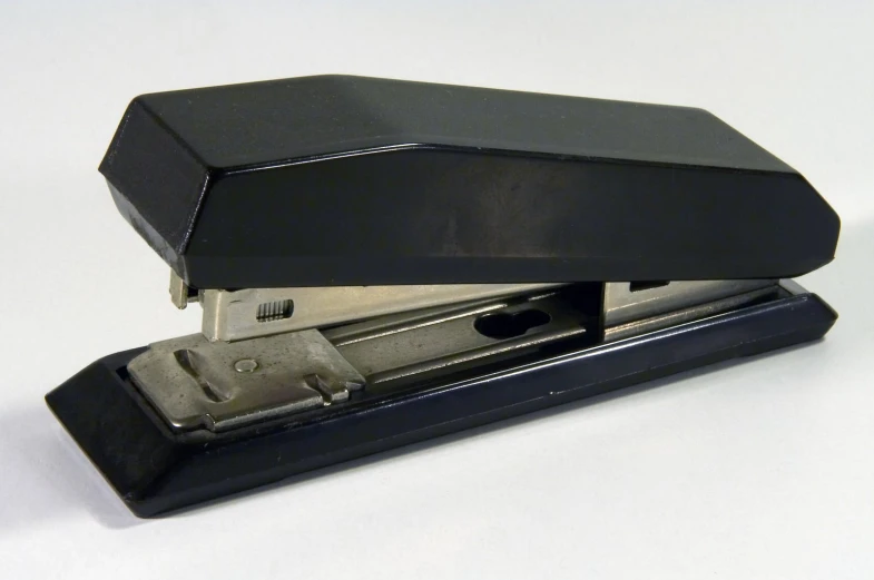 a black stapler sitting on top of a white counter