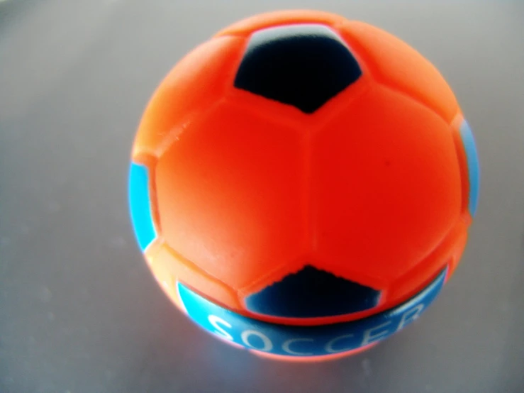 a closeup of an orange soccer ball on a gray surface