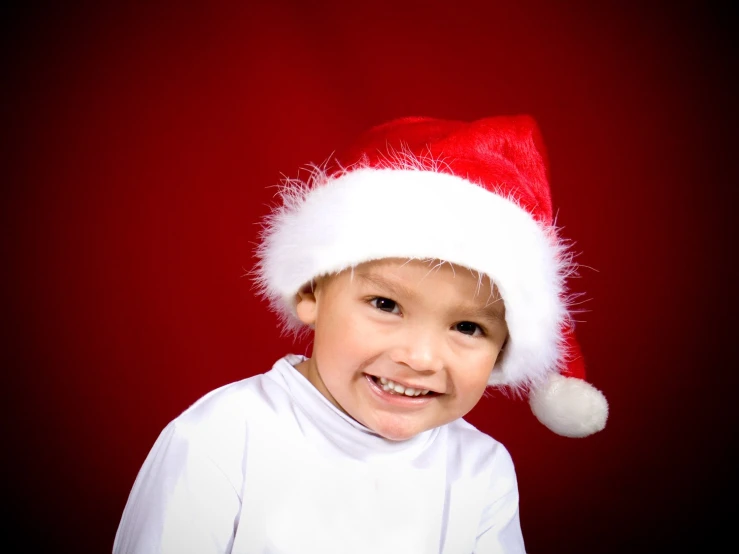 a small child in white outfit with santa hat