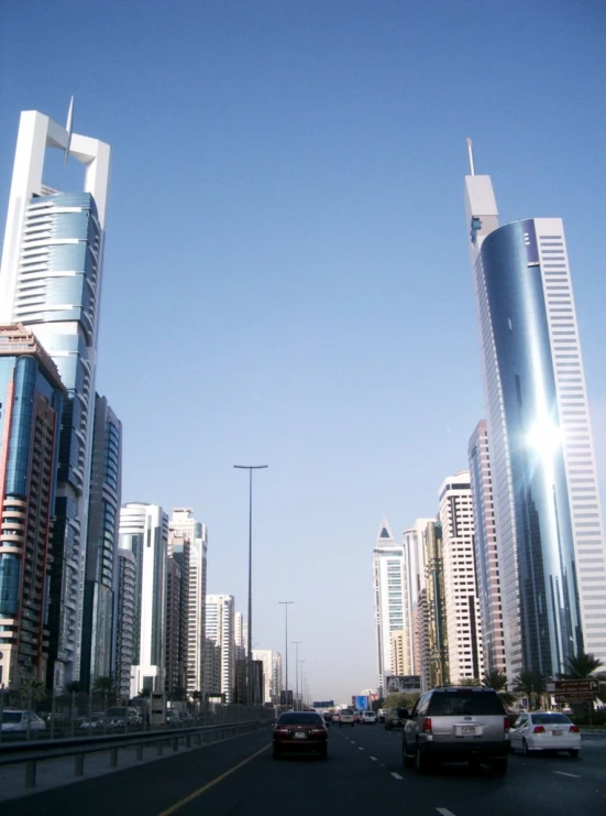 traffic passing by tall buildings with bright sunshine reflecting off them