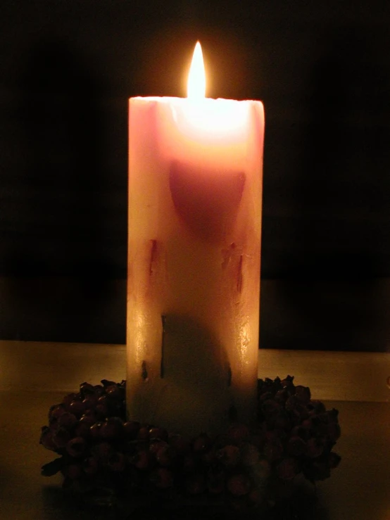 a close up of a lit candle near some flowers