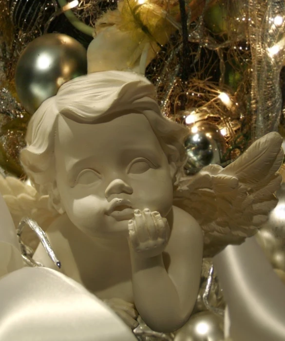 a little angel statue on display in front of christmas decorations