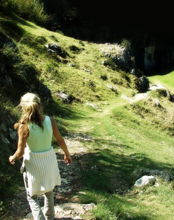 a woman walking up a path next to grass