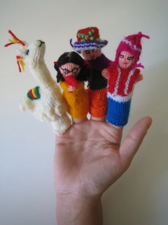 four knit toy figures held in the palm of someone