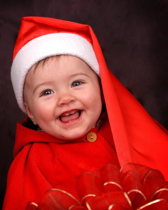 an adorable baby in a red blanket and santa hat