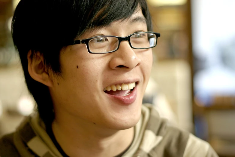 an asian guy with glasses is smiling for the camera