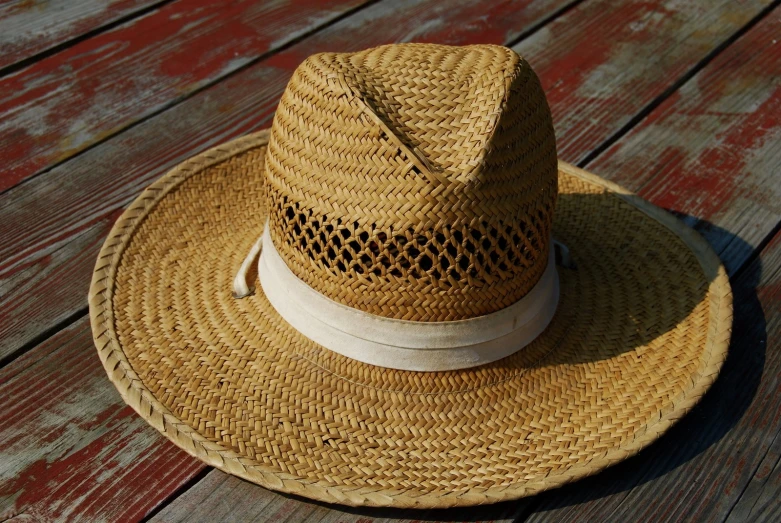a straw hat on a wooden table is made to look like a cowboy hat