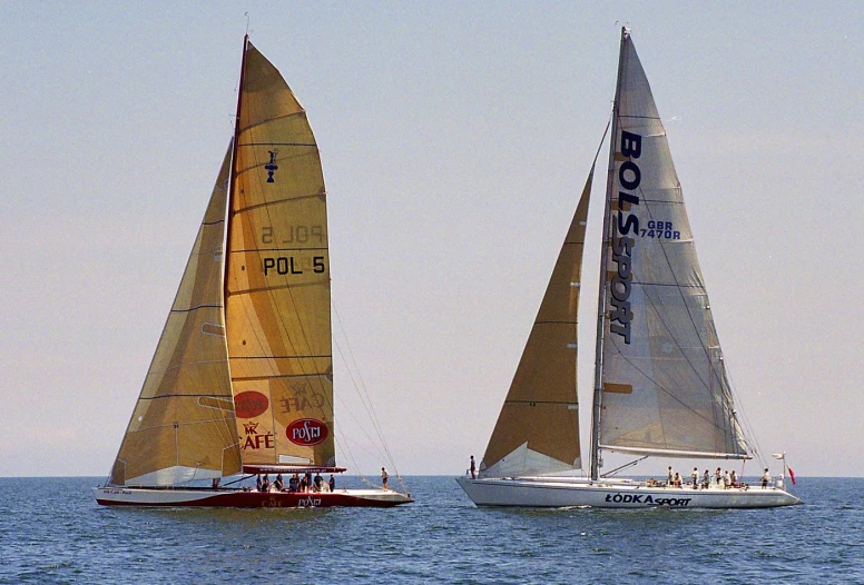 two sailboats sailing in the ocean on a clear day