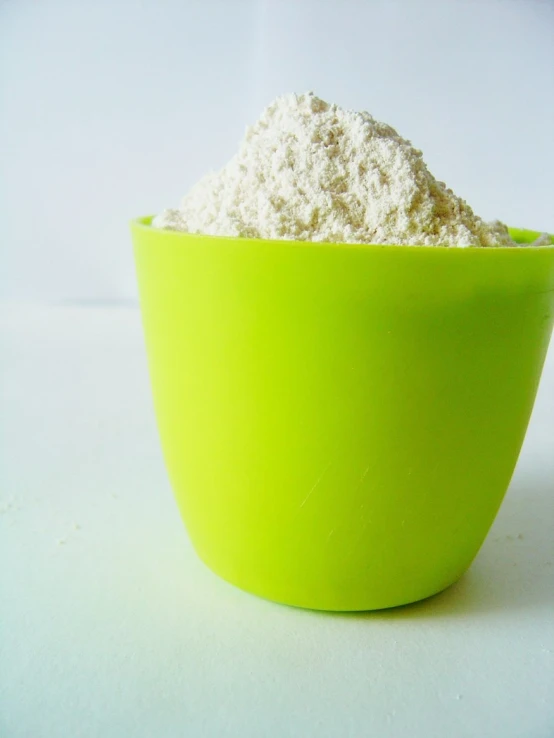 a green bowl filled with white powder on a table