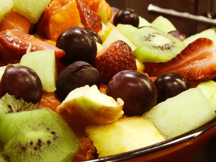 a bowl full of fruit that includes kiwis, strawberries and bananas