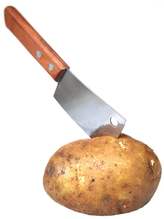 a small potato is being held with a chef knife