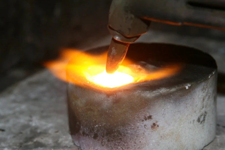 a person welding a piece of steel with yellow and red colored fire coming out