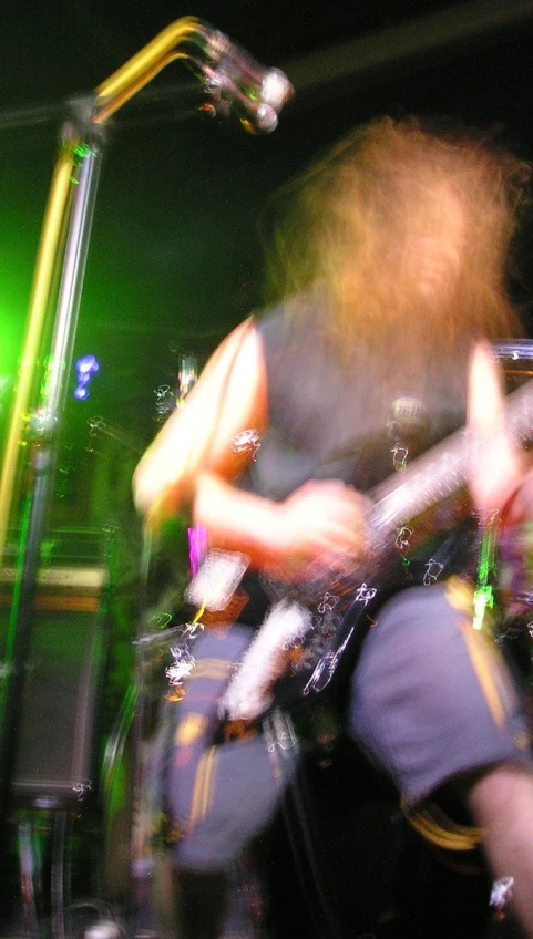 a band with long hair playing guitars at a concert