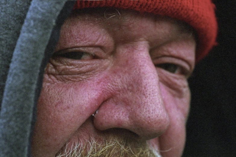 a bearded man with a hat holding a cigarette in his hand