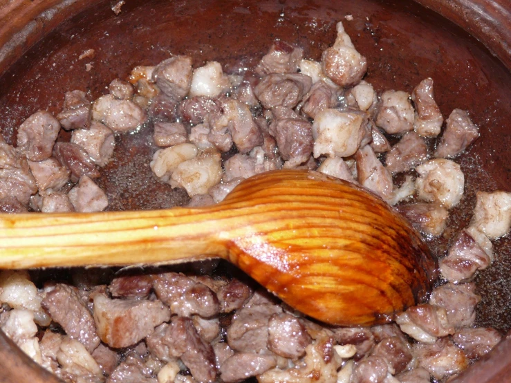 closeup of wooden spoon in pot full of chopped meat