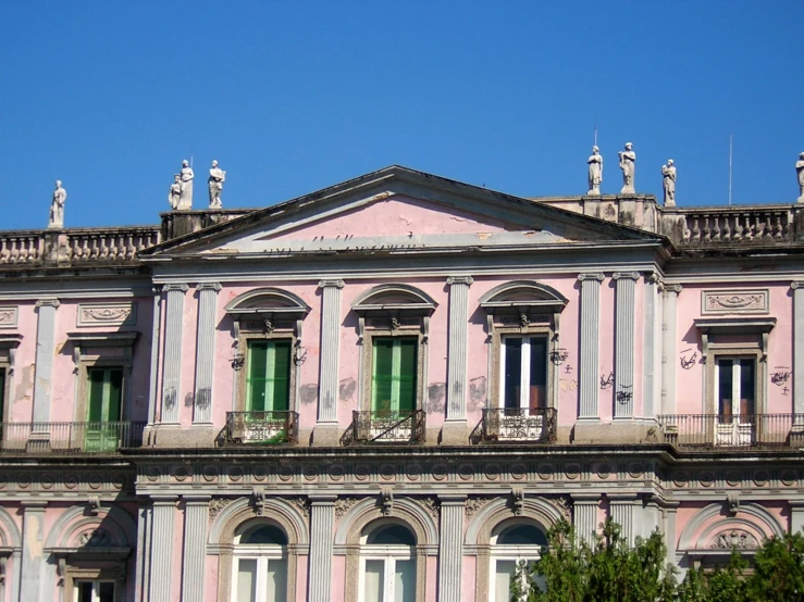 a pink and white building with several green windows