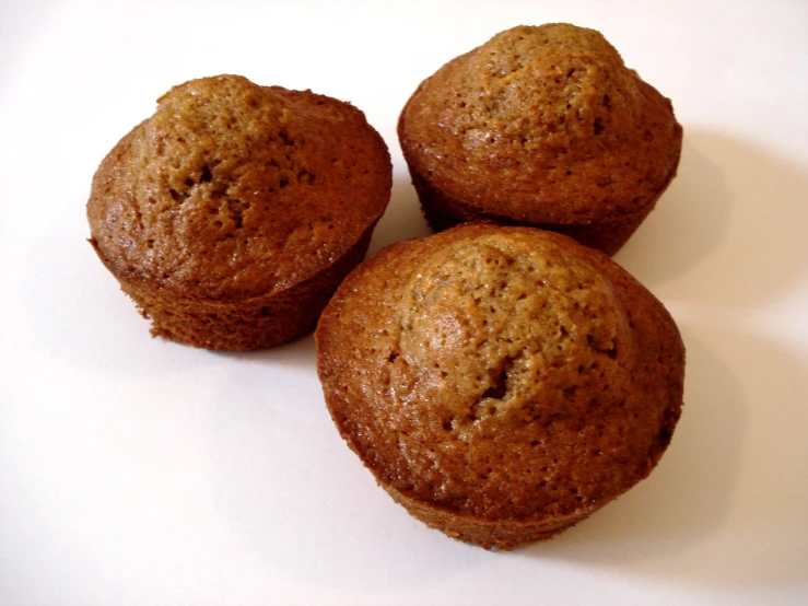 three muffins sitting on a white surface with one muffin in the middle of three