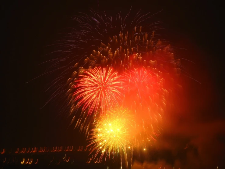red, white and gold fireworks on a dark night with black sky