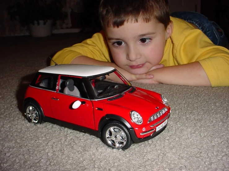 a child laying on the floor near a toy car