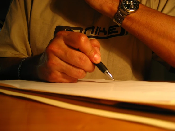 a person holds a pen and writes on paper