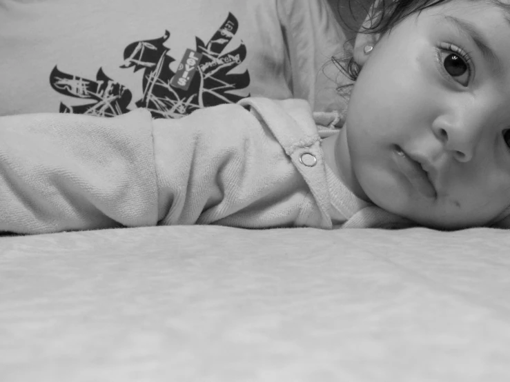 an adorable little girl laying on top of a bed