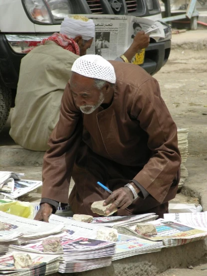 an older man looking at newspapers while sitting down