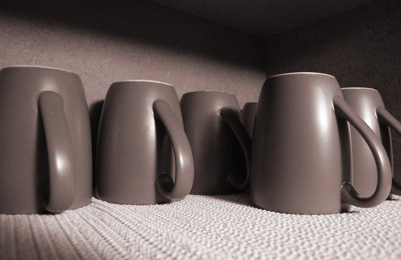 a row of coffee mugs are arranged against a wall