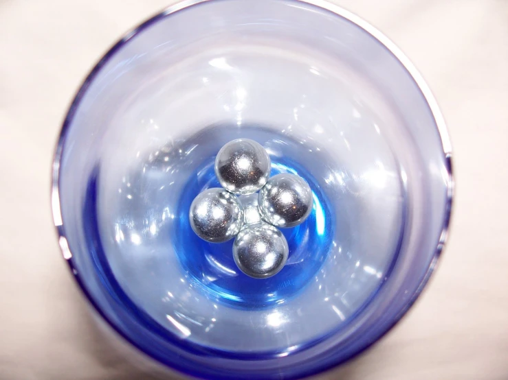 a close up of a blue vase with silver balls in it