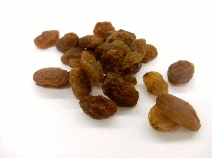 peeled raisins on white surface with scattered other raisins