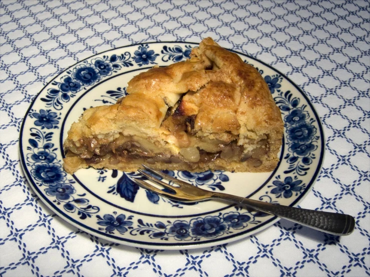 a piece of pie on a blue and white plate with a fork on it