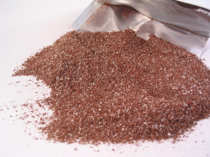 a bag of ground flakes next to a metallic spoon