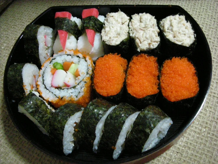 a black plate topped with lots of sushi