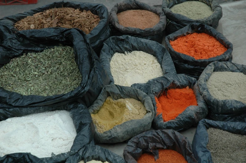 many bags filled with different spices sitting on a counter