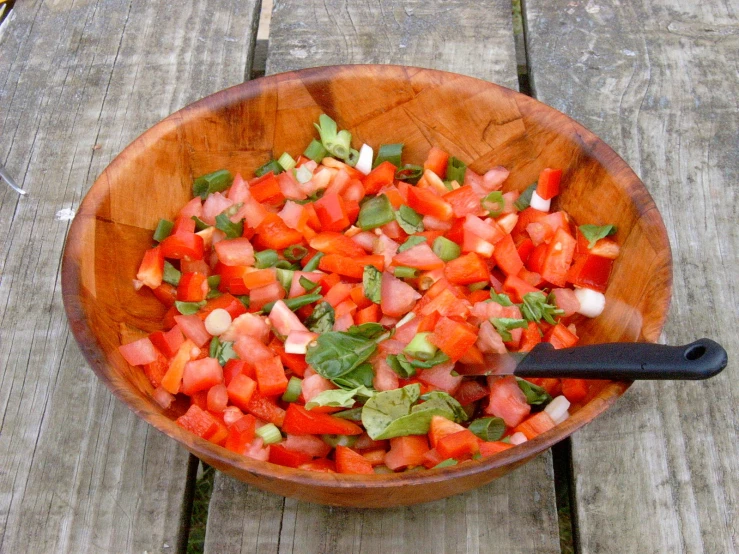 a bowl full of chopped vegetables sits on a wooden deck