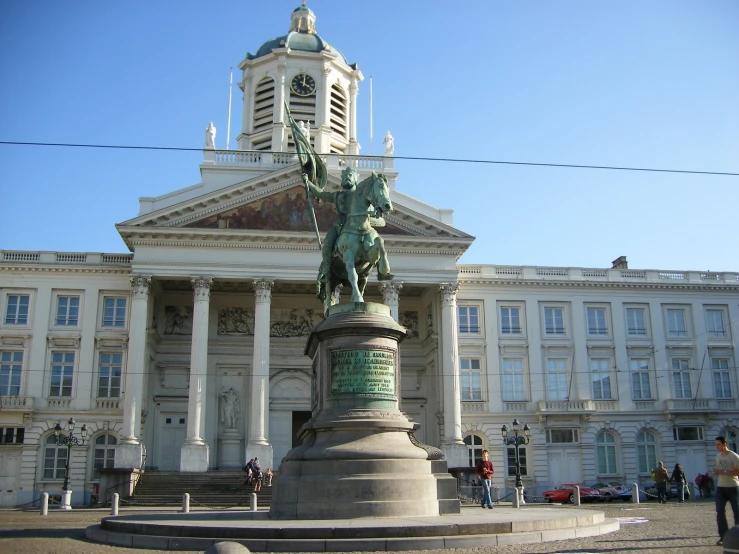 a statue stands outside of a building with a clock