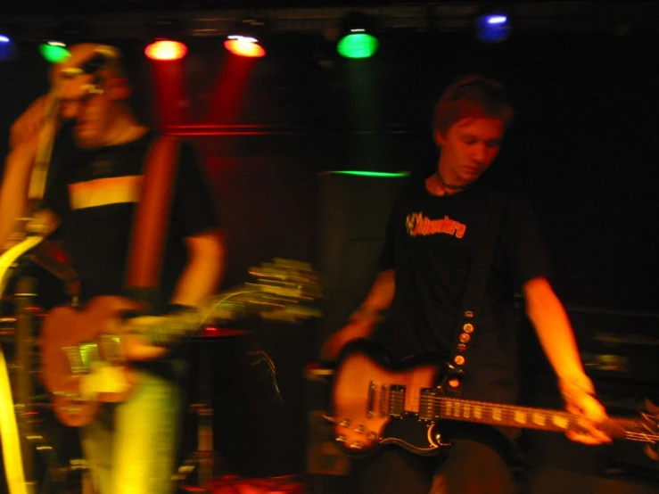 two young men play guitar on stage