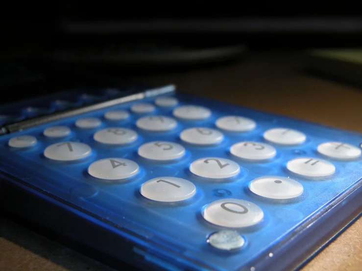 a close up of a blue calculator sitting on top of a wooden table