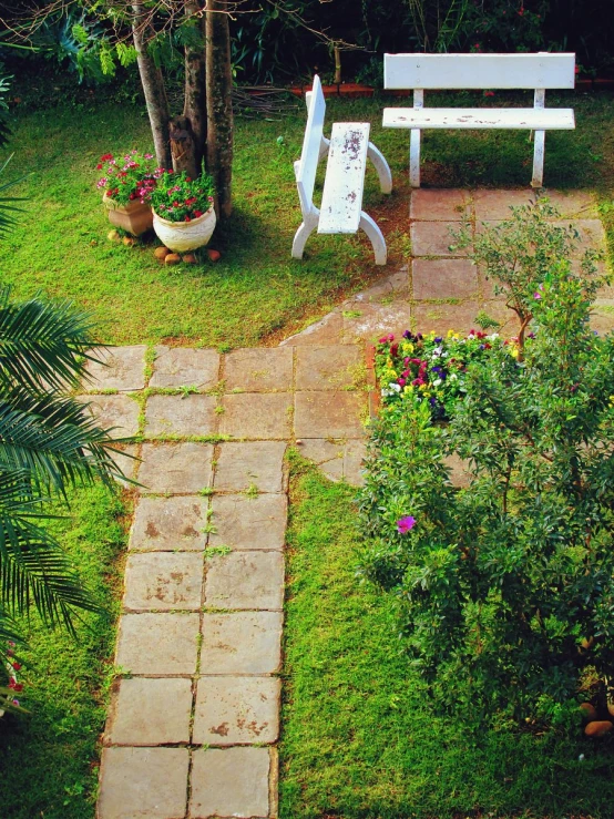 a garden with lawn and steps leading to a white bench