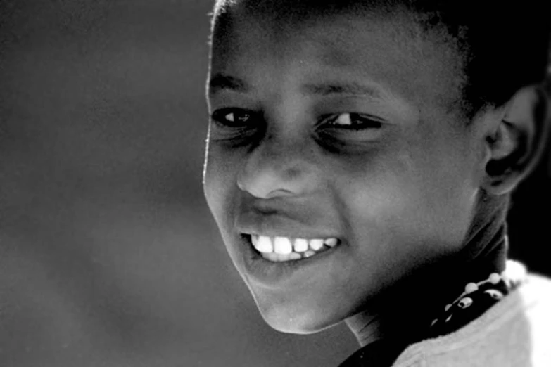 black and white pograph of smiling child wearing a collar