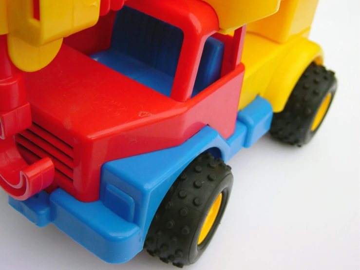 plastic vehicles in multicolored and yellow on white surface