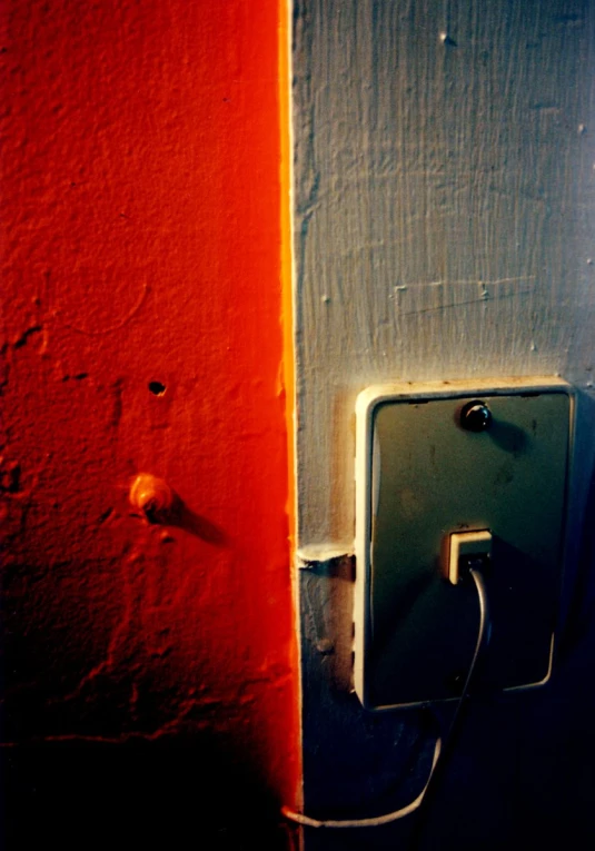 this is a picture of the front of a door with a light switch in between it and an orange wall behind
