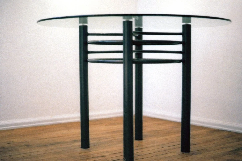 a black table with a glass top sitting on top of a wooden floor