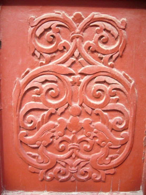 a red, carved pattern on the side of an old building