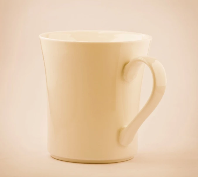 a white mug sits alone against a plain beige background