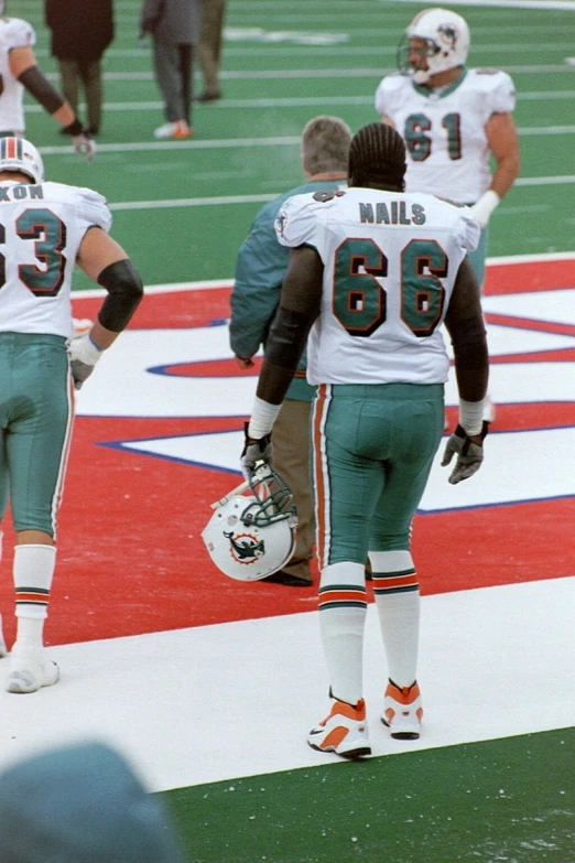 two football players standing on the field wearing numbers and numbers