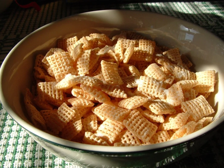 a white bowl with cheetos that is on a green checkered tablecloth